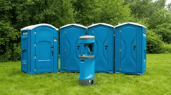 Four blue portable toilets and a matching hand washing station on grass near trees, a common sight at local outdoor events in Ogden, UT